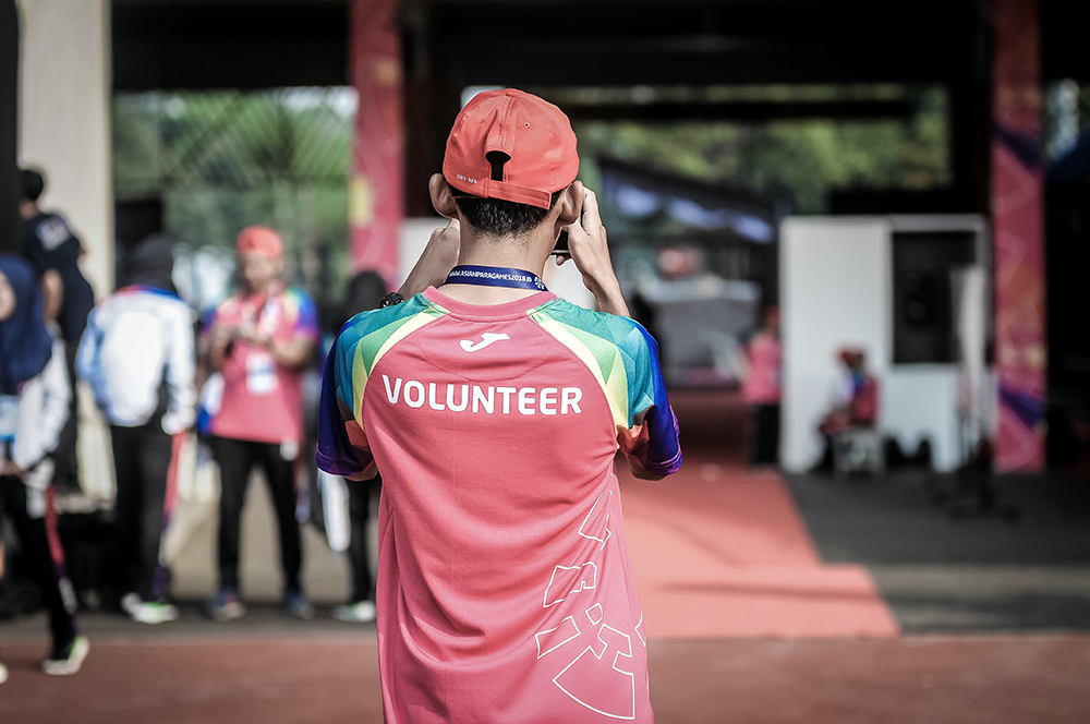 male taking a photo, wearing a shirt that says Volunteer