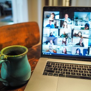 coffee mug in front of a laptop with a video call on the screen