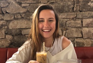 Emma Upton smiling and drinking an iced coffee
